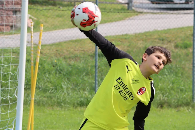 Joven portero con equipación del AC Milan despejando un balón durante el entrenamiento